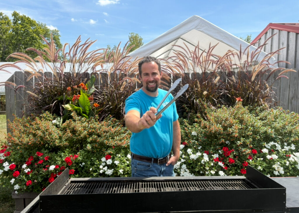 jeff with tongs standing at a grill
