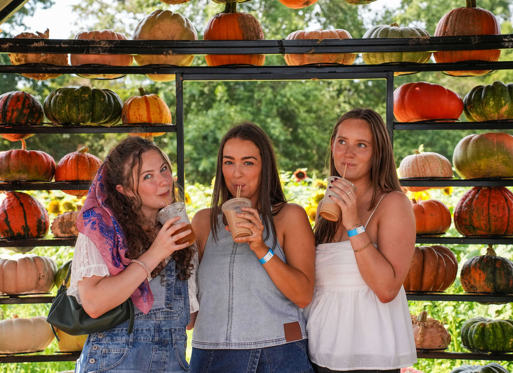 girls inside pumpkin house drinking fall drinks